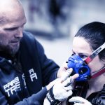 Asiantuntija laittamassa hengitysanalysaattorin maskia Krista Pärmäkosken naamalle liittyen alkamassa olevaan juoksumattotestiin suksilla tehden.