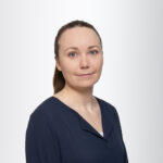 Lähikuva Nanne-Mari Luukkaisesta. Ruskeahiuksinen nainen, tukka taakse vedettynä, katsoo kameraan. Päällä tummansininen paita.
